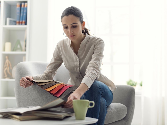 Woman sitting looking at fabric swatches and magazines.